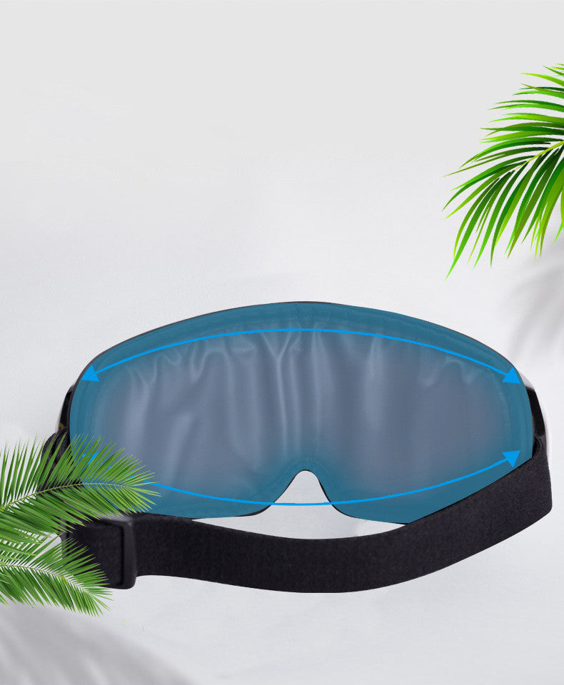 Blue sleep mask with black strap on a white background with green leaves