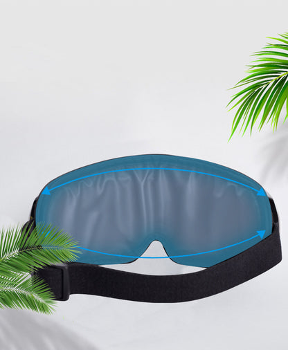 Blue sleep mask with black strap on a white background with green leaves