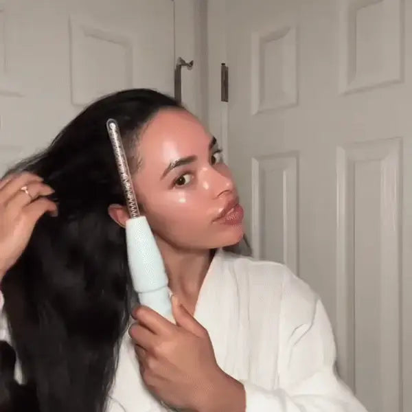 Woman using a hair straightener in a bathroom setting